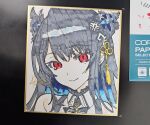  1girl bare_shoulders black_hair blue_hair closed_mouth commentary hair_between_eyes hololive hololive_english horns kutata long_hair looking_at_viewer multicolored_hair nerissa_ravencroft nerissa_ravencroft_(1st_costume) photo_(medium) red_eyes shikishi signature smile solo traditional_media two-tone_hair upper_body 