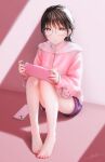 1girl bangs blush brown_hair cellphone day full_body glasses handheld_game_console highres holding holding_handheld_game_console knees_up long_hair long_sleeves looking_at_viewer nintendo_switch ojay_tkym original parted_lips phone pink_sweater purple_shorts red_eyes ribbon-trimmed_sleeves ribbon_trim shorts signature sitting smartphone solo sunlight sweater 