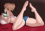  1girl anklet arm_support artist_name barefoot blonde_hair cushion fate/grand_order fate_(series) green_eyes jewelry long_hair looking_at_viewer looking_back lying mordred_(fate) nintendo_switch on_stomach scrunchie short_shorts shorts shoulder_blades sidelocks solo strapless tube_top zealyush 