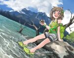  1girl :d arm_support backpack bag bangs bare_shoulders cloud crocs dutch_angle freckles girutea green_footwear green_shirt hair_ornament hairclip holding indie_virtual_youtuber lake lily_hopkins mountain nature open_mouth outdoors photo-referenced shirt shorts sitting sky sleeveless sleeveless_shirt smile solo virtual_youtuber water 