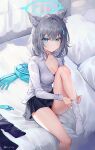  1girl animal_ears bare_legs blue_archive blue_eyes breasts cleavage closed_mouth cross_hair_ornament dressing grey_hair hair_ornament halo highres knee_up looking_at_viewer medium_breasts on_bed putting_on_legwear rity scarf scarf_removed shiroko_(blue_archive) shirt short_hair sitting solo thighs white_shirt 