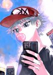  1boy black_shirt blue_eyes bubble_blowing cellphone chewing_gum commentary hat highres holding holding_phone hunter_x_hunter killua_zoldyck male_focus outdoors phone red_headwear shenshan_laolin shirt short_hair smartphone solo symbol-only_commentary white_hair 
