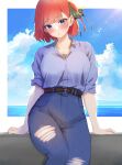  1girl arms_at_sides belt blue_eyes blue_shirt blush breasts butterfly_hair_ornament denim go-toubun_no_hanayome hair_ornament head_tilt high-waist_pants highres jeans kakato_0 large_breasts looking_at_viewer nakano_nino ocean pants parted_lips red_hair shirt sitting sky solo torn_clothes torn_jeans torn_pants 