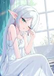  1girl book book_stack breasts curtains day elf frieren green_eyes highres long_hair looking_at_viewer mikaze_oto nightgown one_eye_closed pointy_ears sitting sleeping sleeveless small_breasts sousou_no_frieren strap_slip thick_eyebrows white_hair white_nightgown window 