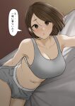  1girl :o absurdres bed blush breasts brown_hair cleavage collarbone dolphin_shorts grey_footwear grey_sports_bra highres large_breasts looking_at_viewer lying navel on_side original short_shorts shorts solo speech_bubble sports_bra tantanmen72 translation_request 