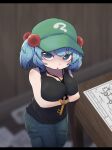  1girl alternate_costume arms_under_breasts black_tank_top blue_eyes blue_hair blue_pants blurry blurry_background blush breast_lift breasts commentary_request cowboy_shot crossed_arms flat_cap green_headwear hair_bobbles hair_ornament hat highres jewelry kawashiro_nitori key_necklace large_breasts letterboxed looking_at_viewer medium_bangs medium_hair necklace onaji_(sokudo_seigen) open_mouth pants solo table tank_top touhou two_side_up wooden_table wooden_wall 