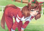  1girl animal_ears bent_over brown_eyes brown_hair ear_covers ear_ribbon grass green_ribbon horse_ears horse_girl horse_tail jacket long_hair long_sleeves looking_at_viewer miri_(ago550421) nice_nature_(umamusume) outdoors red_track_suit ribbon short_hair solo sweat tail tracen_training_uniform track_jacket track_suit twintails umamusume unzipped zipper 