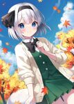  1girl autumn autumn_leaves black_hairband black_ribbon blue_eyes blush buttons cardigan closed_mouth collared_shirt cowboy_shot day green_skirt green_vest grey_hair hair_ribbon hairband highres hitodama konpaku_youmu konpaku_youmu_(ghost) leaf looking_at_viewer maple_leaf open_cardigan open_clothes outdoors pleated_skirt ribbon shirt short_hair skirt smile solo suzuno_naru touhou vest white_cardigan white_shirt 