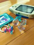  blue_gemstone funahashi_(nkmmmmr) game_boy_advance gem handheld_game_console highres keychain no_humans pokemon pokemon_(creature) porygon2 realistic white_gemstone wooden_floor 