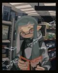  1girl agent_3_(splatoon) black_border book border closed_mouth dr_mice fish green_hair grey_hoodie highres holding holding_book hood hood_down hoodie indoors inkling inkling_girl long_hair looking_at_viewer orange_eyes pointy_ears shop solo splatoon_(series) tentacle_hair twitter_username 