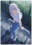  1girl ahoge blue_pants commentary cropped_shirt denim fence from_above full_body grass grey_eyes grey_hair highres jeans kamo_kamen looking_at_viewer m_(kamo_kamen) midriff navel original pants shirt shoes sitting sneakers solo t-shirt 