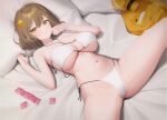  1girl anis_(nikke) anis_(sparkling_summer)_(nikke) aya_(lezon) bed_sheet bikini breasts brown_eyes brown_hair condom condom_packet_strip condom_wrapper crotch eyepatch_bikini goddess_of_victory:_nikke hair_ornament hairclip highres jacket jacket_removed jewelry large_breasts looking_at_viewer lying navel on_back parted_lips pendant pillow solo spread_legs stomach swimsuit thighs white_bikini 