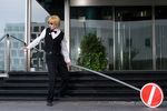  1boy black_pants blonde_hair bow bowtie cosplay durarara!! full_body heiwajima_shizuo heiwajima_shizuo_(cosplay) male male_focus outdoors pants photo real road_sign sign solo stairs sunglasses vest waistcoat 