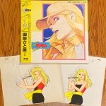  1980s_(style) 1girl animation_cel blonde_hair bow_accessory highres laserdisc_cover microphone nora_scholar photo_(medium) retro_artstyle singing strapless tube_top twinkle_nora_rock_me! yellow_eyes 