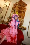  1girl asian bow chandelier cosplay couch crescent dress female hat highres kneeling long_hair looking_back mirror mob_cap patchouli_knowledge photo purple_hair red_upholstery ribbon robe slippers solo table tenshi_myu thighhighs touhou 
