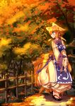 animal_ears blonde_hair blue_eyes breast_squeeze breasts clog_sandals dress fence fox_ears fox_tail hat hat_removed headwear_removed highres koha large_breasts long_sleeves looking_back multiple_tails solo sunset tabard tail touhou tree v_arms white_dress wide_sleeves yakumo_ran 