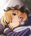  1girl blonde_hair blush closed_mouth commentary dress fumei_(mugendai) hat long_hair long_sleeves looking_at_viewer lying maribel_hearn mob_cap on_stomach purple_dress purple_eyes sleeve_cuffs sleeve_garter smile solo touhou white_hat 