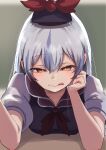  1girl blurry blurry_background commentary delta_delta dress elbow_rest grey_hair hair_between_eyes hat head_rest highres kamishirasawa_keine licking_lips long_hair looking_at_viewer reaching reaching_towards_viewer short_sleeves solo table tongue tongue_out touhou white_sleeves yellow_eyes 