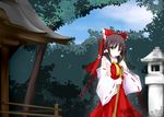  ascot bow broom brown_eyes brown_hair dd_mayohara detached_sleeves dress hair_bow hair_ribbon hair_tubes hakurei_reimu holding long_hair looking_at_viewer red_dress ribbon shadow shrine solo standing stone_lantern touhou tree 