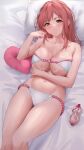  1girl absurdres bare_arms bare_shoulders bed_sheet bikini blush breasts closed_mouth collarbone commentary_request dead_or_alive dead_or_alive_5 dead_or_alive_xtreme heart heart-shaped_pillow highres hoki1314 honoka_(doa) large_breasts long_hair looking_at_viewer lotion lotion_bottle lying navel on_back pillow pink_eyes pink_hair shiny_skin smile solo stomach swimsuit thighs 