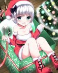  1girl :d bangs bare_shoulders belt blush boots box christmas christmas_tree collarbone commentary_request cross-laced_footwear detached_sleeves dress eyebrows_visible_through_hair from_above fur-trimmed_dress fur-trimmed_hat green_eyes hat highres in_box in_container indoors konpaku_youmu konpaku_youmu_(ghost) looking_at_viewer open_mouth red_footwear santa_costume santa_hat scabbard shamuichi sheath short_hair silver_hair sitting smile solo strapless strapless_dress sword touhou weapon wooden_floor 