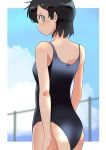  1girl absurdres ass black_hair black_one-piece_swimsuit blue_sky blurry blurry_background cloud commentary_request cowboy_shot fence grey_eyes haida_katsuretsu highres looking_at_viewer looking_back one-piece_swimsuit original school_swimsuit short_hair sky solo swimsuit 