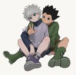  2boys :/ black_hair black_shorts blue_eyes blue_shirt boots brown_eyes closed_mouth commentary elbow_on_knee gon_freecss green_boots green_jacket green_shorts grey_shirt head_tilt highres hunter_x_hunter invisible_chair jacket killua_zoldyck layered_sleeves long_sleeves male_focus multiple_boys orange_trim purple_shoes sha_nato shirt shoes short_hair short_over_long_sleeves short_sleeves shorts simple_background sitting sleeve_cuffs smile spiked_hair symbol-only_commentary three-finger_salute turtleneck white_background white_hair widow's_peak 