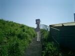  1girl chain-link_fence commentary_request day dress fence grass grey_dress long_hair narue original outdoors photo_background short_dress sideways_glance solo standing wide_shot 