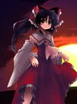  bare_shoulders black_hair blush bow brown_eyes collar detached_sleeves dress hair_bow hakurei_reimu long_hair looking_at_viewer ponytail red_dress scot shin_(new) solo sunset touhou 