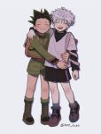  2boys :d backpack bag black_hair black_shirt black_shorts boots brown_footwear closed_eyes gon_freecss green_jacket green_shorts grin hat_babo high_collar highres hug hunter_x_hunter jacket killua_zoldyck multiple_boys open_mouth shirt short_hair shorts simple_background smile spiked_hair teeth twitter_username upper_teeth_only white_background white_hair white_shirt 