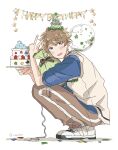  1boy ahoge am_ber balloon birthday_cake blue_eyes brown_hair cake commentary_request confetti ensemble_stars! food from_side fruit full_body gift happy_birthday hat highres looking_at_viewer male_focus open_mouth party_hat short_hair simple_background smile solo squatting star_(symbol) strawberry takamine_midori twitter_username white_background 