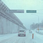 building car circle_k_(store) day highres lamppost motor_vehicle no_humans outdoors road road_sign sign simon_stalenhag snow sports_utility_vehicle swedish_machines swedish_text traffic tree van winter 