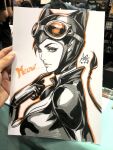  1girl art_tools_in_frame artist's_hand_in_frame batman_(series) black_hair black_shirt breasts catwoman cleavage commentary dc_comics english_commentary english_text from_side goggles goggles_on_head highres large_breasts looking_at_viewer marker_(medium) orange-tinted_eyewear orange_outline outline parted_lips partially_colored photo_(medium) shirt signature stanley_lau tinted_eyewear traditional_media upper_body 
