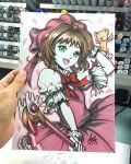 1girl art_tools_in_frame artist's_hand_in_frame bow cardcaptor_sakura commentary dress english_commentary fuuin_no_tsue gloves hat highres holding holding_wand kero_(cardcaptor_sakura) kinomoto_sakura kinomoto_sakura_(magician) magical_girl marker_(medium) photo_(medium) pink_dress pink_hat red_bow signature solo stanley_lau traditional_media wand white_gloves 