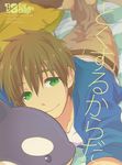  brown_hair cover cover_page doujin_cover free! green_eyes lying male_focus memeo_(candy_house) on_stomach pillow smile solo stuffed_animal stuffed_toy stuffed_whale tachibana_makoto 