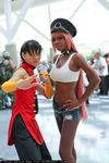  2girls asian black_hair chinese_clothes cosplay crop_top dark_skin hands_on_hips midriff multiple_girls navel non-asian photo pink_hair poison_(final_fight) short_shorts shorts street_fighter 