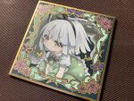  1girl absurdres black_bow black_bowtie black_hairband blush bow bowtie collared_shirt commentary_request frilled_skirt frills green_eyes green_skirt green_vest grey_hair hairband highres hitodama konpaku_youmu konpaku_youmu_(ghost) looking_at_viewer mosho photo_(medium) puffy_short_sleeves puffy_sleeves shikishi shirt short_sleeves skirt skirt_set solo touhou traditional_media vest white_shirt 