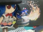  1girl black_background blue_hair fire flaming_sword flaming_weapon from_side full_body fumo_(doll) fumoteria highres hinanawi_tenshi holding holding_sword holding_weapon kaname-ishi leaning_forward long_hair peach_hat_ornament photo_(medium) simple_background solo standing sword sword_of_hisou touhou traditional_media weapon 