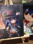  1girl blue_hair closed_mouth commentary fire flaming_sword flaming_weapon fumo_(doll) fumoteria highres hinanawi_tenshi holding holding_sword holding_weapon long_hair looking_at_viewer photo_(medium) red_eyes smile solo sword sword_of_hisou touhou traditional_media weapon 