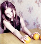  black_hair child food fruit hands head_tilt holding holding_food holding_fruit long_hair orange photo reference_photo solo table upper_body 