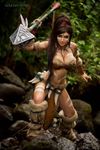  boots bra breasts brown_hair chains cleavage collar cosplay fang jessica_nigri jungle league_of_legends long_hair looking_at_viewer nature nidalee outdoor outdoors photo ponytail skirt spear stone tan_skin tattoo weapon 
