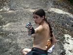  1girl braid breasts cosplay gloves gun lara_croft looking_back photo tomb_raider topless weapon 
