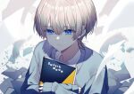  1boy absurdres blonde_hair blue_cardigan blue_eyes blurry cardigan closed_mouth commentary_request daifuku_mame_(kageroudt33) dated depth_of_field frown gradient_hair highres holding holding_sketchbook looking_at_viewer male_focus multicolored_hair original paper shirt signature sketchbook solo tears twitter_username white_shirt wolf_cut 
