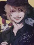  1boy animal animal_on_shoulder bat_(animal) black_hat black_shirt brown_eyes brown_hair cat character_request collared_shirt commentary_request dated grin hand_up happy_birthday hat highres holding jiz_(pffbq) l'arc~en~ciel looking_at_viewer male_focus muted_color real_life realistic shirt short_hair simple_background smile upper_body witch_hat yellow_background yeti_(creature) 