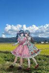  2girls black_hair blue_bow blue_dress blunt_bangs blush bow brown_hair brown_shoes cherry closed_eyes closed_mouth collared_dress commentary_request dress dress_bow food frilled_dress frilled_sleeves frills fruit full_body hair_bow hairband highres hug hug_from_behind loafers lolita_fashion lolita_hairband long_hair looking_at_another mary_janes multiple_girls open_mouth original photo_background pink_bow pink_dress platform_shoes print_dress puffy_short_sleeves puffy_sleeves red_shoes rounded_collar rural shirt shoes short_sleeves smile socks standing strawberry sweet_lolita tear_troughs tsuzuki_amy twintails white_shirt white_socks yuri 