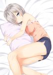  bare_arms bare_shoulders bed bed_sheet blue_eyes blue_shorts breasts casual eyes_visible_through_hair hair_ornament hair_over_one_eye hairclip hamakaze_(kantai_collection) highres kantai_collection light_smile looking_at_viewer lying medium_breasts on_side one_eye_closed pillow pillow_hug pink_shirt shirt short_hair shorts solo takehana_note tank_top thighs 