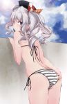  1girl ass ass_grab beret bikini black_hat blue_eyes blue_sky cloud commentary_request cowboy_shot day from_behind hat kantai_collection kashima_(kantai_collection) looking_at_viewer looking_back outdoors side-tie_bikini sidelocks silver_hair sky solo striped striped_bikini swimsuit tsurime twintails wall wavy_hair yumesato_makura 