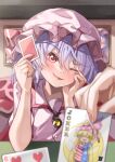  1girl 1other ;d absurdres blue_hair blurry blush brooch card character_print clownpiece commentary depth_of_field elbows_on_table fang female_pov fingernails frills hair_between_eyes hand_on_own_face hands_up happy hat head_tilt highres holding holding_card indoors jewelry joker_(playing_card) long_fingernails mahoro_(minase_mahoro) mob_cap nail_polish one_eye_closed pink_hat pink_shirt playing_card pov red_eyes red_nails red_ribbon remilia_scarlet ribbon shirt smile solo_focus touhou tsurime upper_body yellow_gemstone 