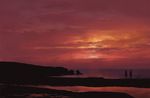  1girl beach cloud cloudy_sky commentary_request facing_away from_behind hat horizon izna_(iznatic) long_hair ocean original outdoors red_sky scenery shore sky standing sunset very_wide_shot 