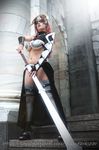  1boy 1girl armor bikini_armor bra breasts claudette_(queen&#039;s_blade) claudette_(queen&#039;s_blade)_(cosplay) cosplay large_breasts long_hair metal_bra panties photo queen&#039;s_blade red_hair standing sword underwear weapon 